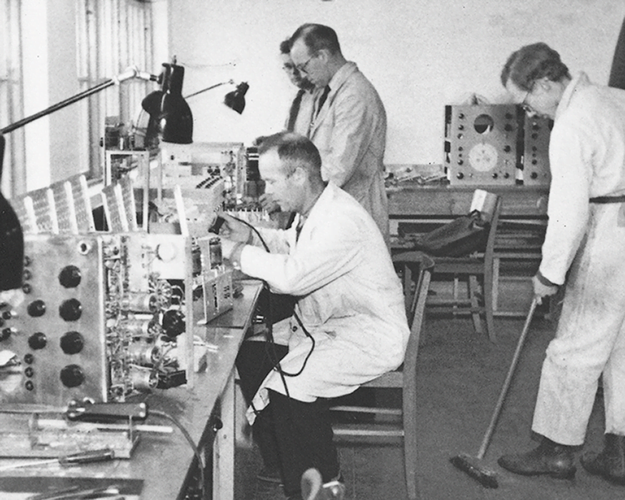 Engineers in the old workshop working, testing – and sweeping!